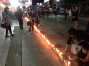 Lighting candles on sidewalk of main street